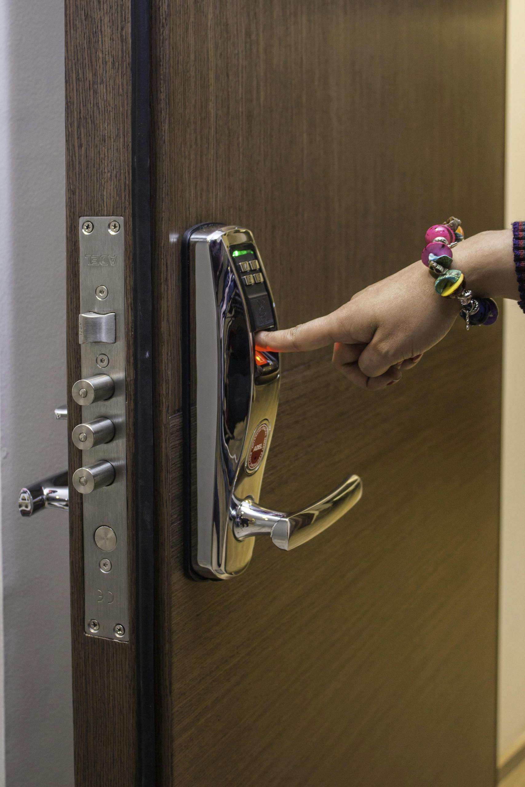 A hand using fingerprint access on a digital security door lock, enhancing safety.